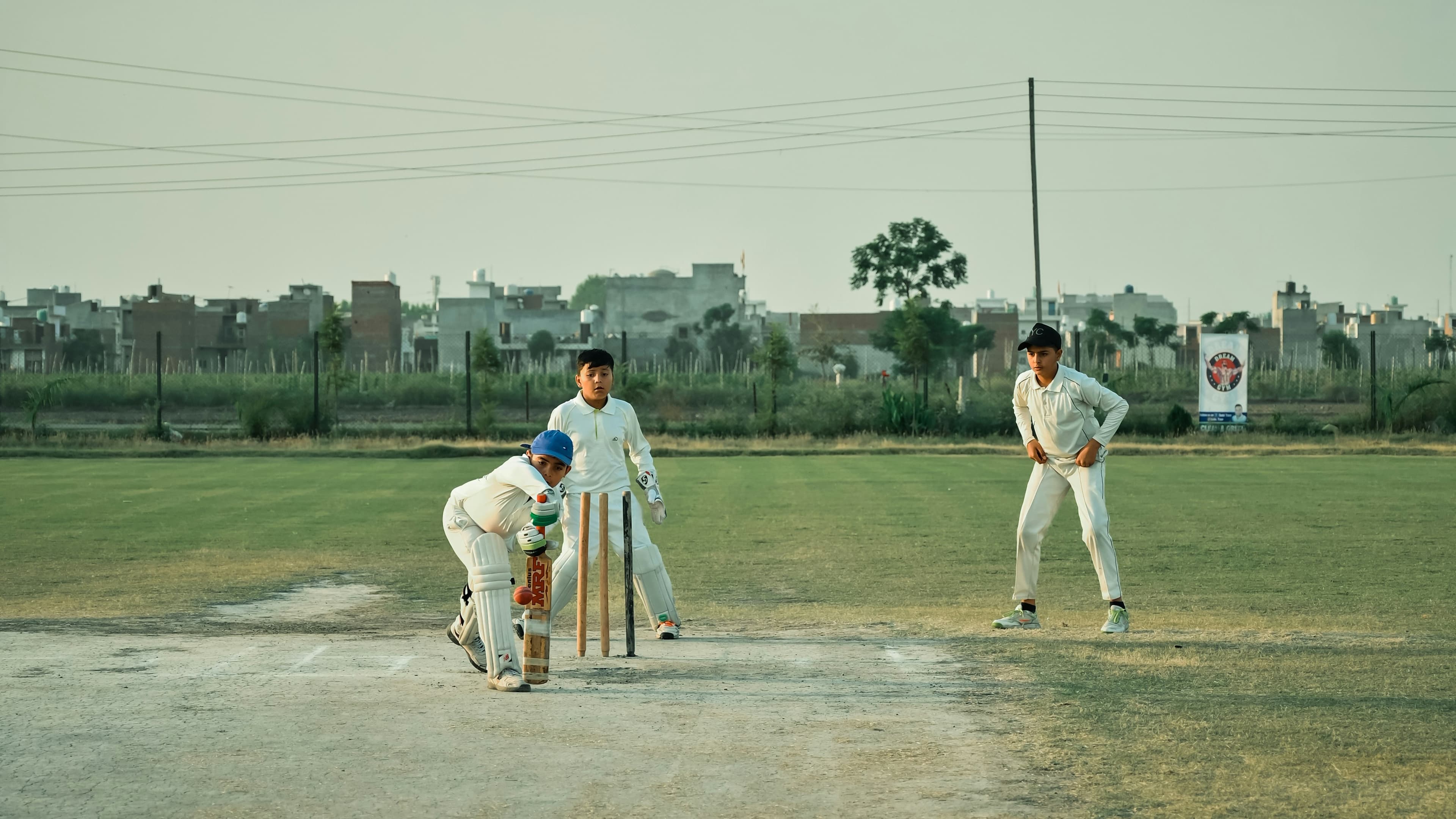 Kids playing cricket together on a field